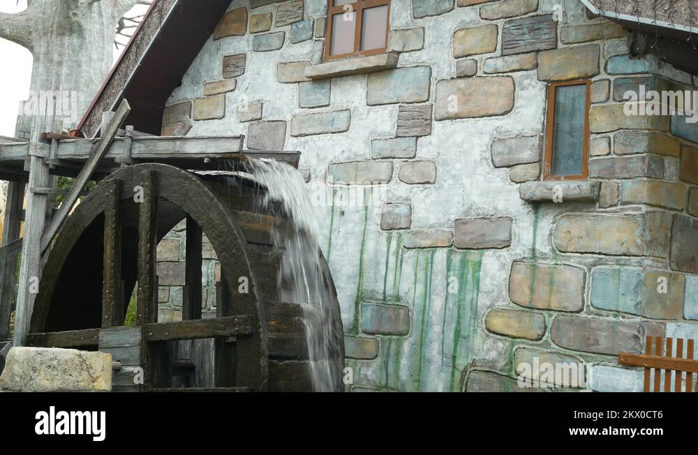 A large wooden wheel of a water mill spins, pumping water. 4k Stock