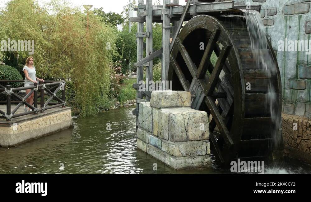 A large wooden wheel of a water mill spins, pumping water. 4k Stock