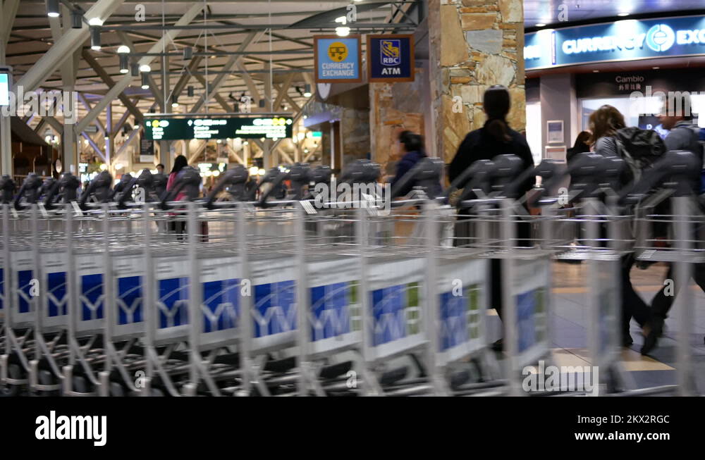 Motion of airport workers moving stacks of luggage carts inside YVR