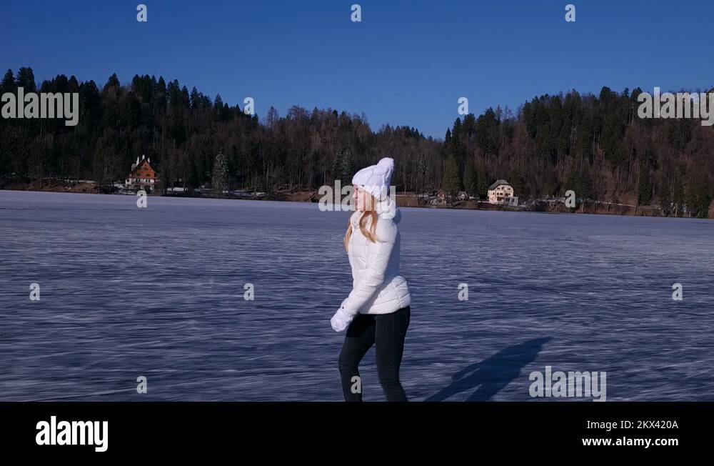 Slow motion Beautiful female model ice skating on a frozen lake Bled