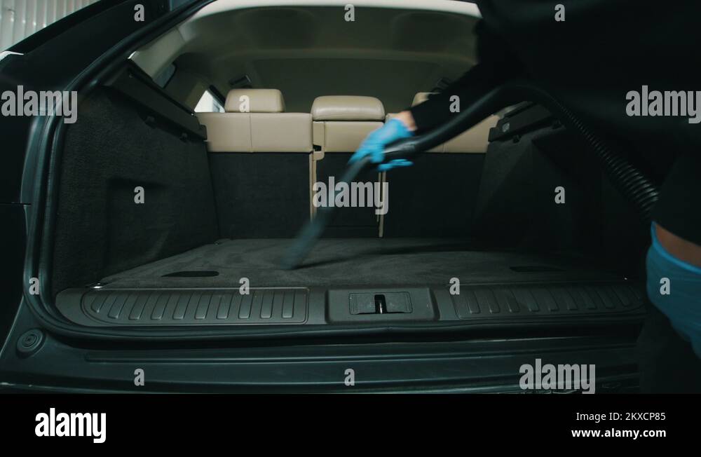 Dry cleaning of trunk, man cleans the car interior with vacuum cleaner