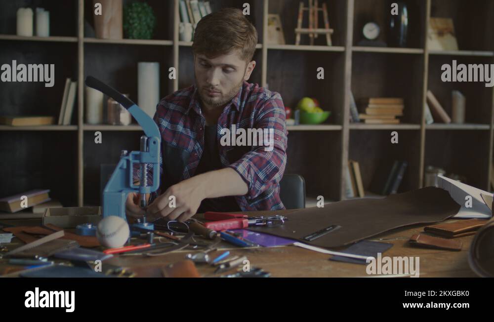 Leather product manufacturing process. Craftsman installing rivet at product Stock Video Footage