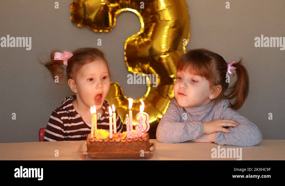 Little girls blows out candles on birthday cake at party. Funny happy