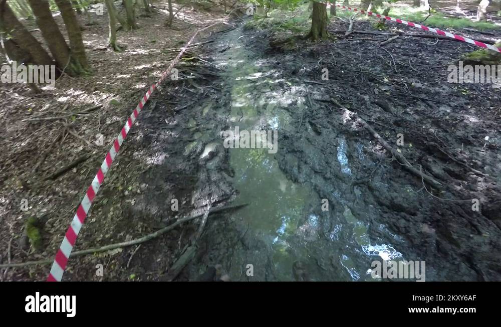 POV a man, clothes covered in mud, walks down a muddy pathway at a