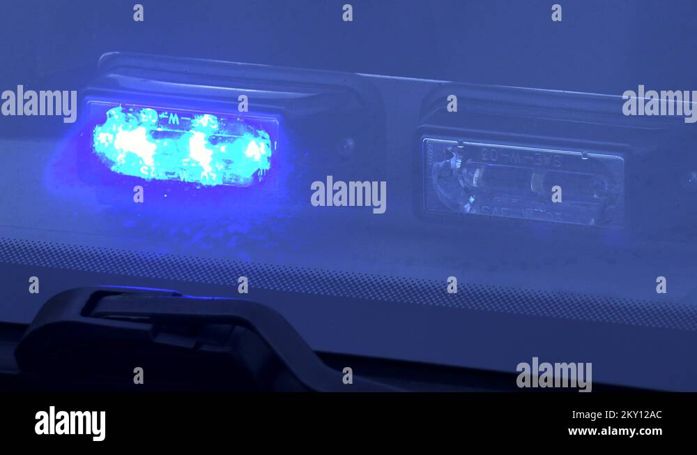 Closeup on a blue warning dashboard light flashing behind a windshield