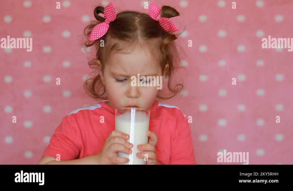 The child does not want to drink milk, takes a sip and frowns. Cute