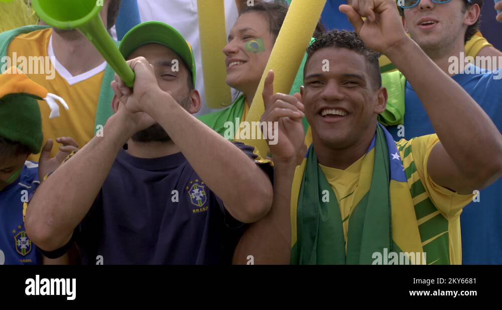 Brazilian football fans dancing and cheering at football match, slow motion Stock Video Footage