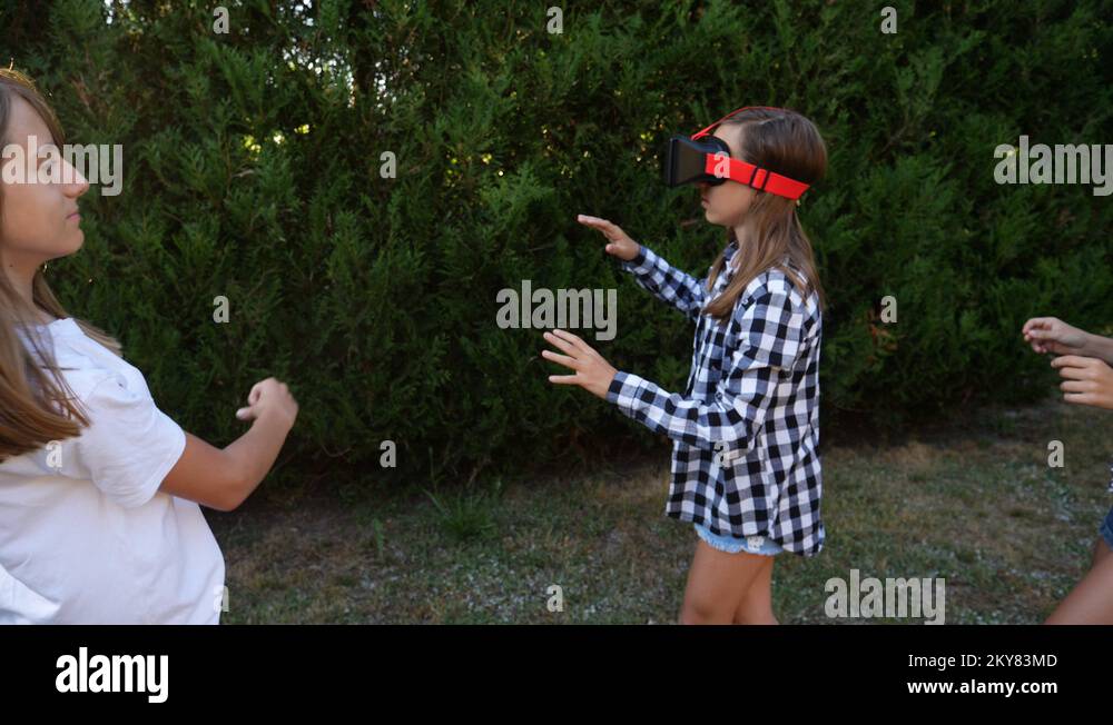 Young girl watch virtual reality in VR glasses teenager twins sisters