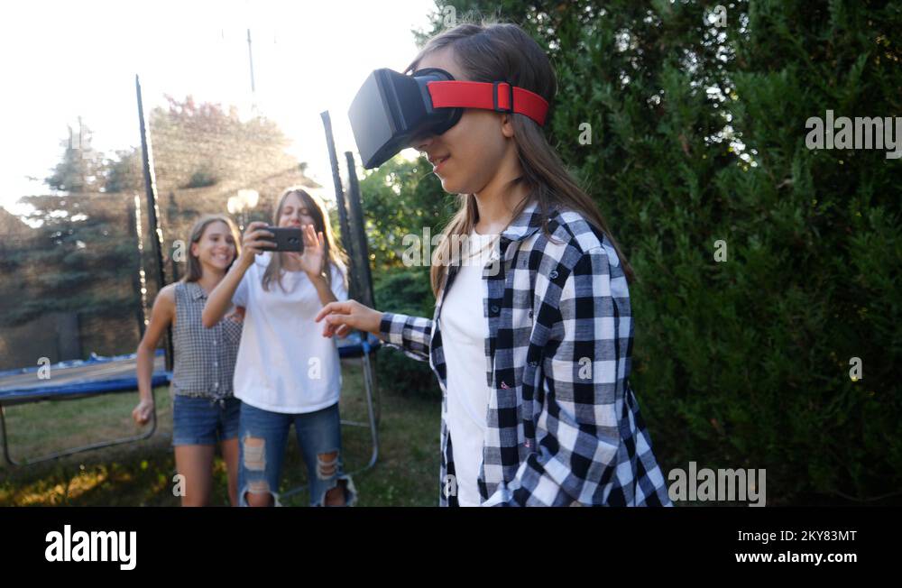 Young girl watch virtual reality in VR glasses teenager twins sisters