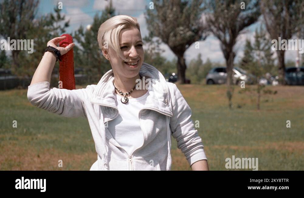 Girl throws her dog round soft toy. Dog jumps into the water, splashing