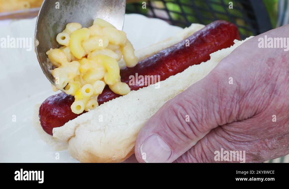 Man puts macaroni and cheese on hot dog Stock Video Footage Alamy