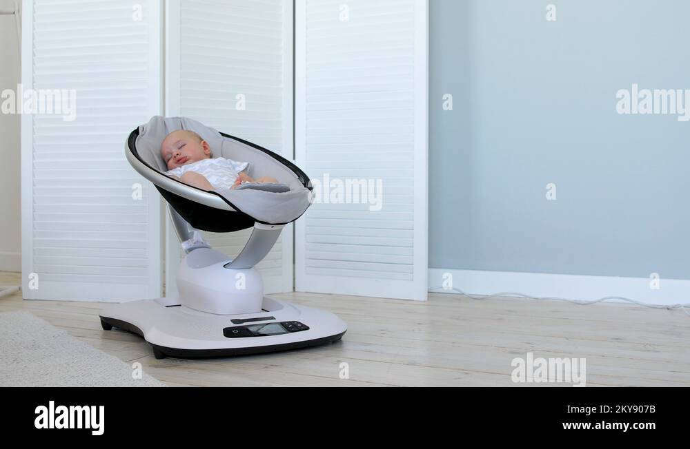 Sweet newborn baby girl sleeping in a bouncer chair in a white room