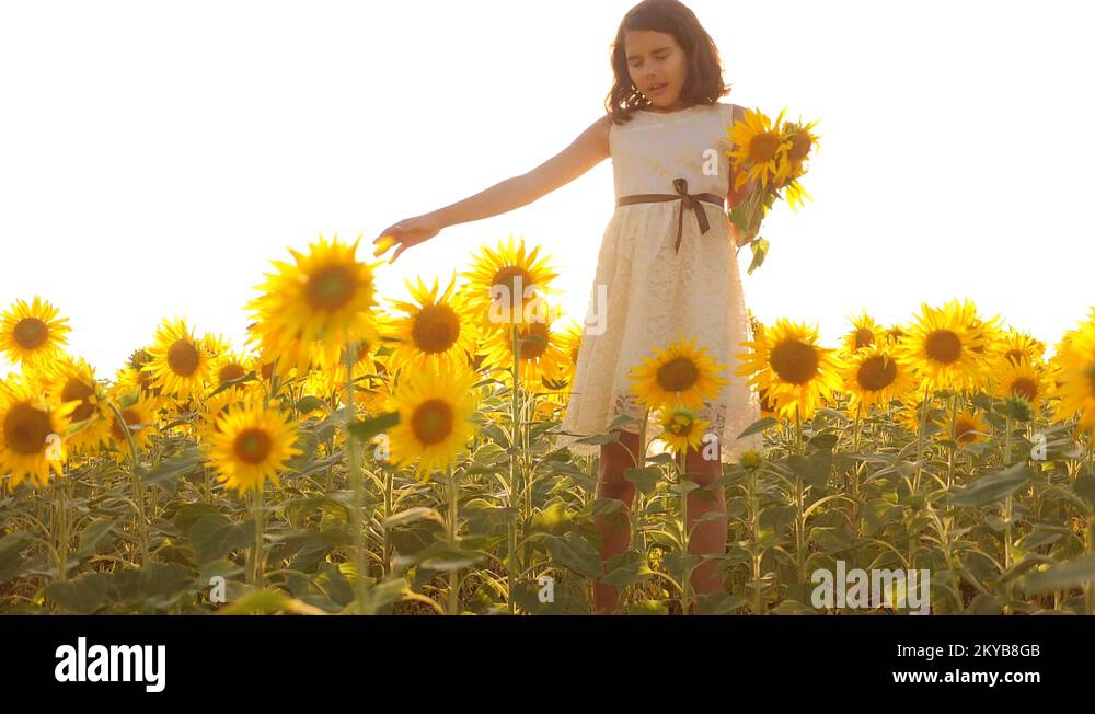 Happy little girl teen smelling a sunflower sneezes allergic to flowers