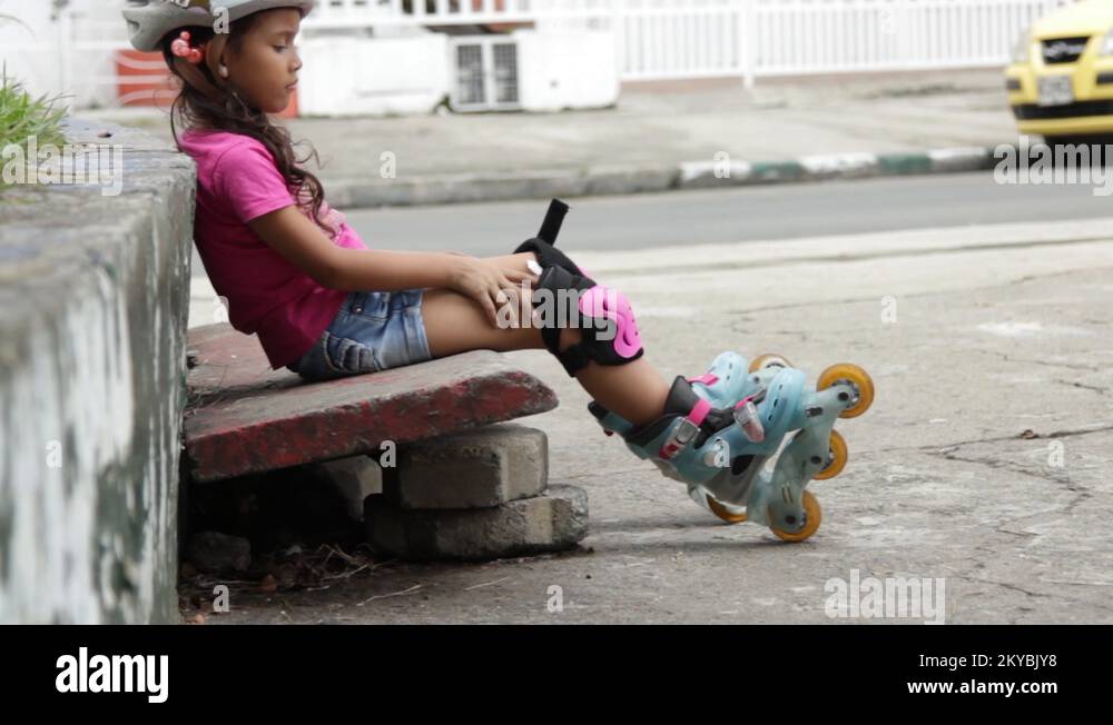 Little girl sitting down wearing roller blades moving legs Stock Video