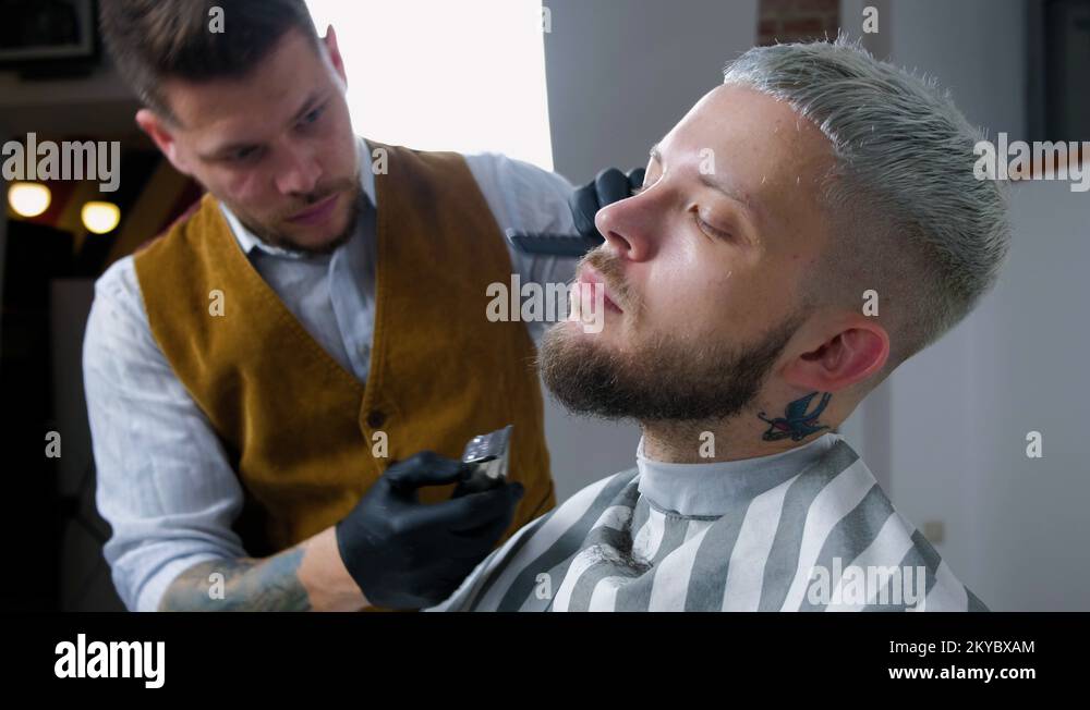 Shaving of beard. Barber cutting men's face hair with beard trimmer at