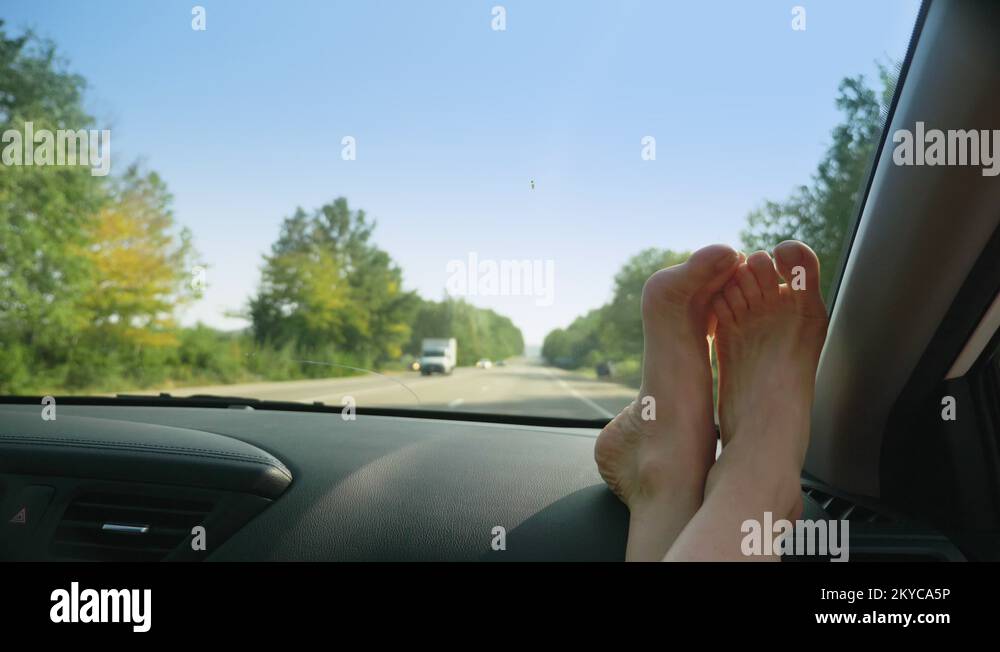 female feet on the dashboard of the car, from the side of the passenger