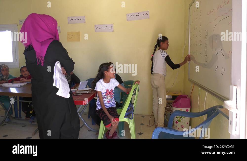 Female pupil writing in Arabic on whiteboard in school classroom, Syria