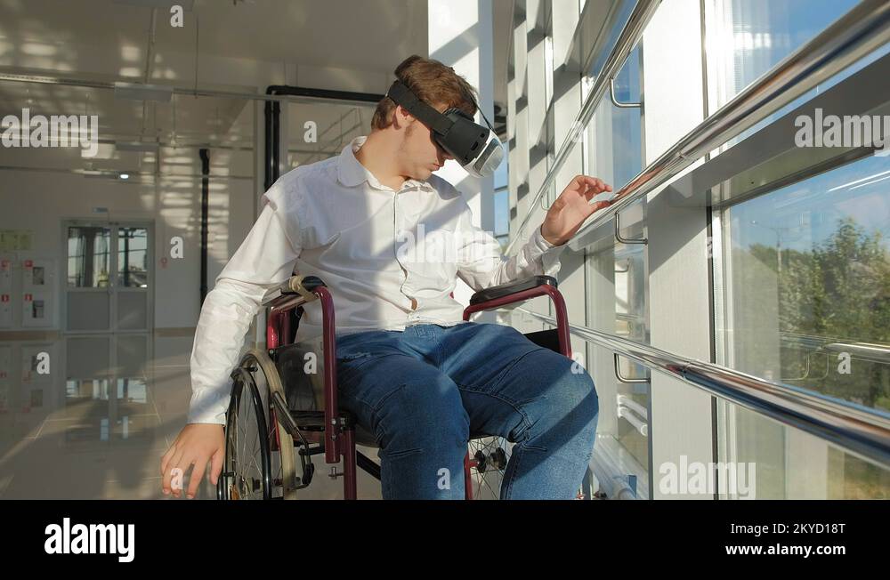 disabled man on a wheelchair at a window uses a helmet of virtual reality Stock Video Footage