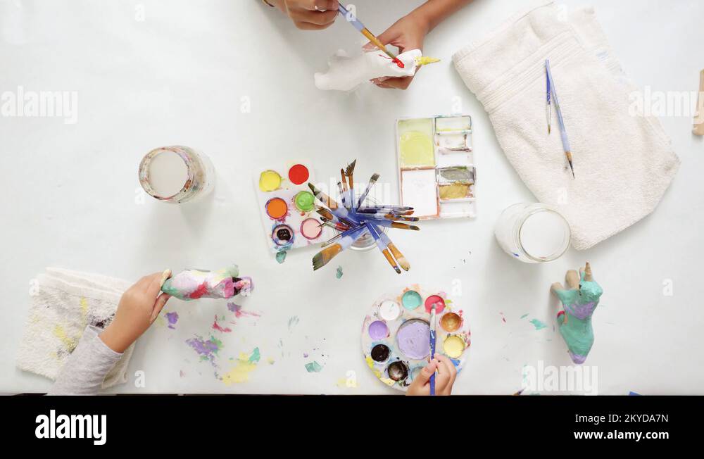 Little girls painting paper mache unicorn with acrylic paint Stock