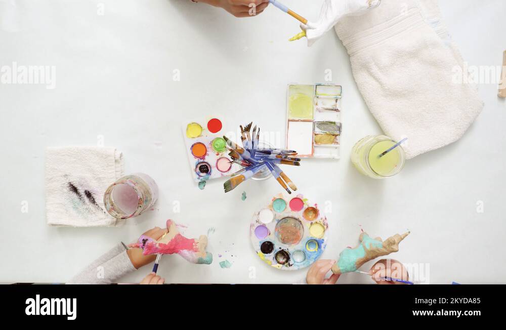 Little girls painting paper mache unicorn with acrylic paint Stock