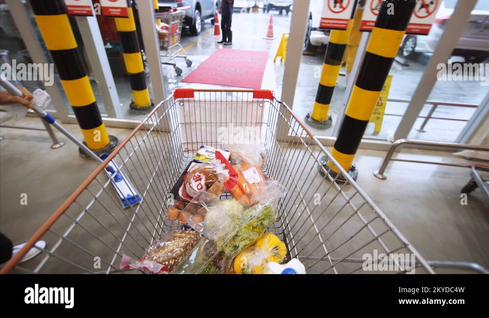 Shopping cart with food move through exit doors. "Macro" hypermarket