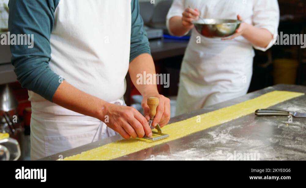 Male and female baker using ravioli stamp on pasta dough 4k Stock Video