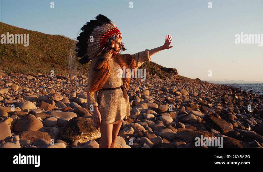 Woman in native american indian headdress moves her hands doing ritual ...