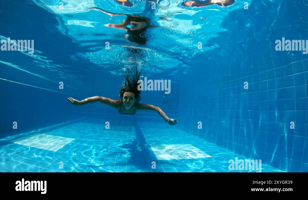 Young lady swimming underwater in the pool. Underwater woman portrait ...