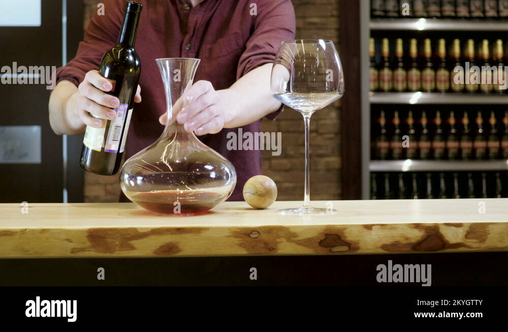 Barman. The bartender pouring red wine from a bottle into the wine