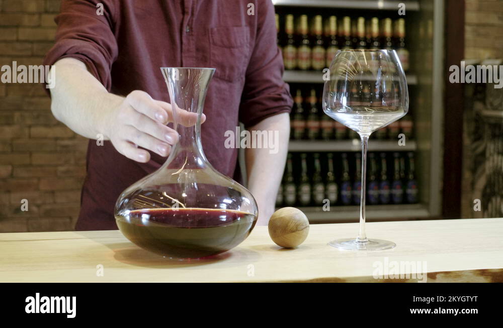 Barman. The bartender pouring red wine from the wine decanter into a