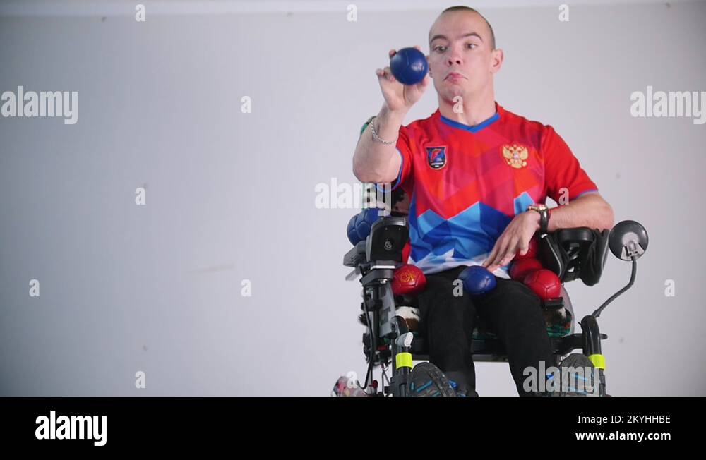A disabled man in a wheelchair. Throwing a blue little ball in the air