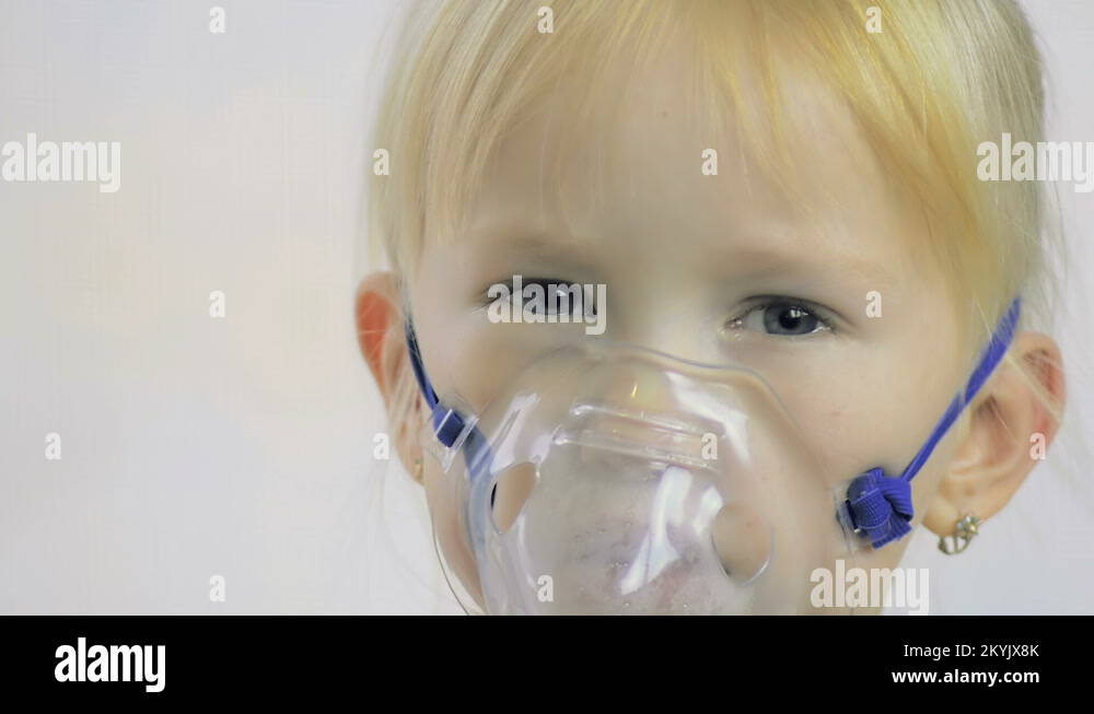 Closeup of a fouryearold girl doing breathing procedures through an