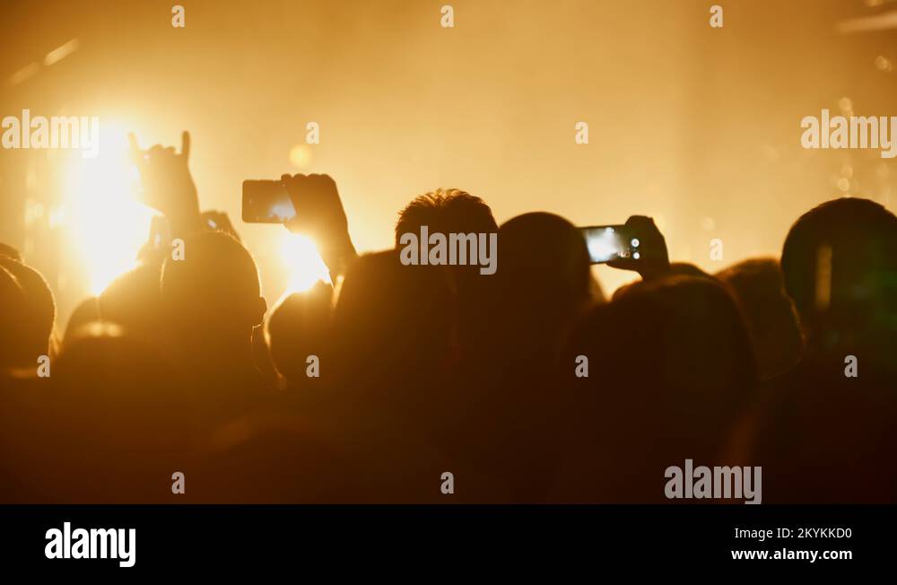 Fans taking video and photos on smart phone at concert strobing