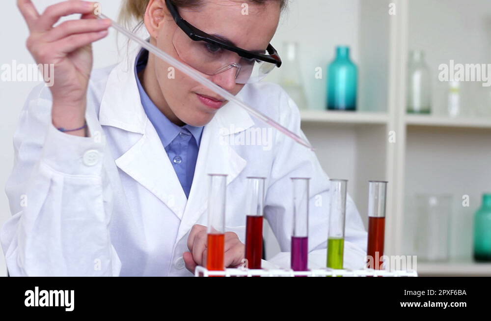 Scientist using pipette to add substance to test tubes with chemicals