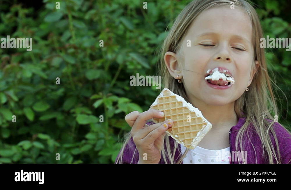 The little girl eating vanilla ice cream and looking at camera