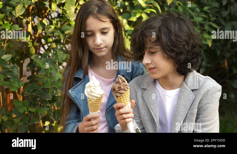 cute teenagers, boy and girl eating ice cream in the park and talking ...