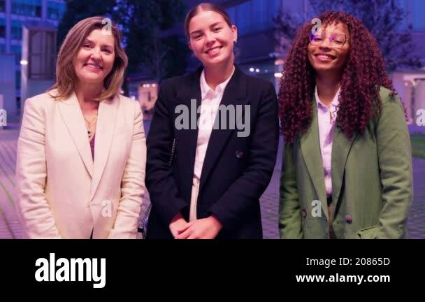 Three women in business attire standing with crossed arms, smiling and ...