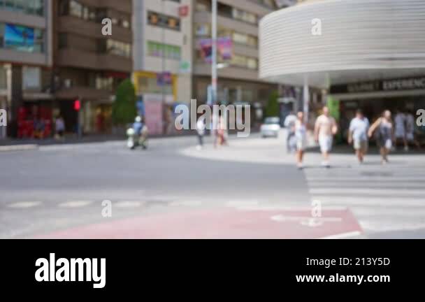 Defocused pedestrians crossing a busy urban street in the daylight with ...