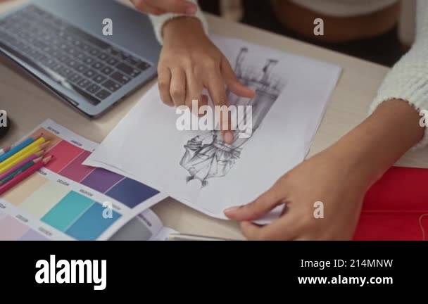 A man and a woman collaborate in a design studio, examining fashion ...