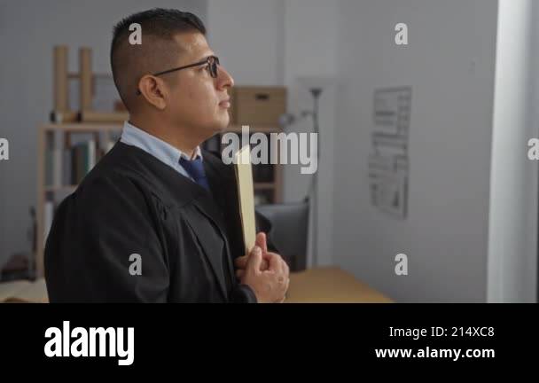 Young hispanic man in judge robe holding folder in a professional ...