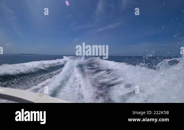 Waves from the engines of a high-speed boat. Rear view. Blue sky, white ...