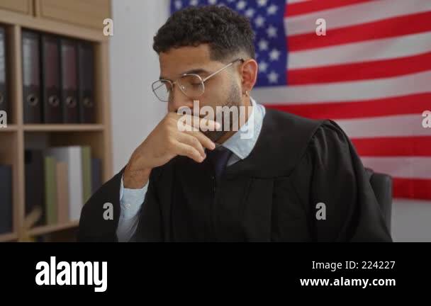 Young man in judge robe thinking seriously while removing glasses in an ...