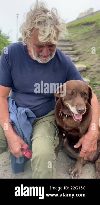 senior man bonding with his dog sitting on stairs in the park Stock ...