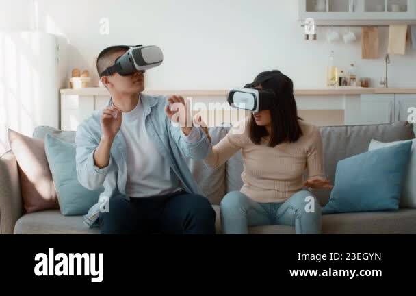 A man and woman are immersed in a virtual reality experience while ...