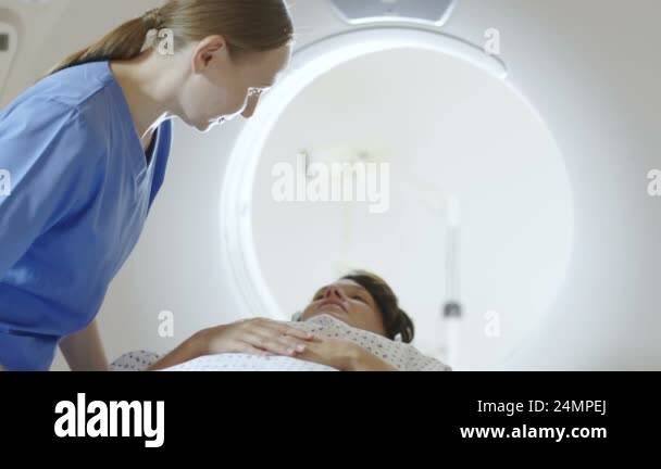 Radiographer comforting patient before computed tomography (CT) scan ...