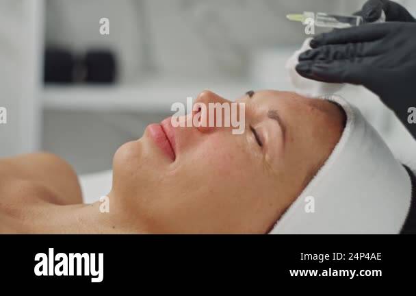 Close-up of a cosmetologist injecting a woman face with precision ...