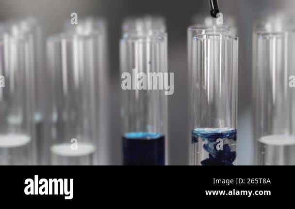 Close-up of a sample of blue liquid falling from a pipette into a test ...