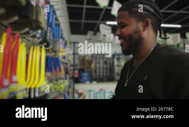 Man in black apron organizing brushes on display shelves in a paint ...