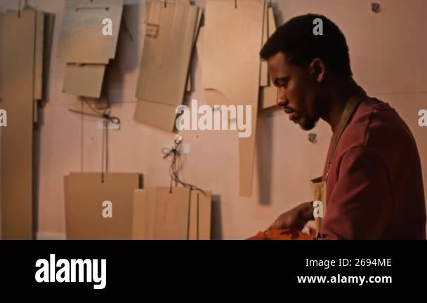 Tilt down shot of young African American craftsman wearing apron ...