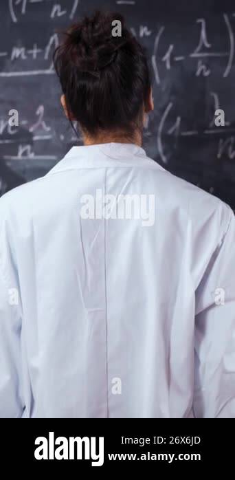 Math Acronym Robe Female student in white robe standing opposite wall chalk board with ...
